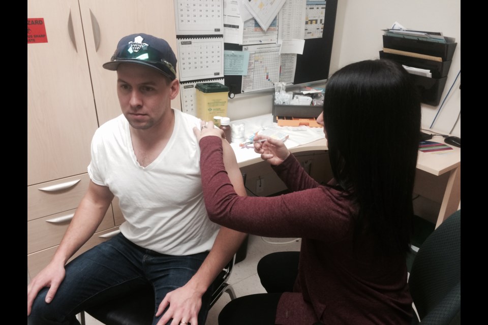 Jessica Taus Public Health Nurse with the Vaccine Preventable Disease Program gives the flu shot to Joshua Rhodenizer