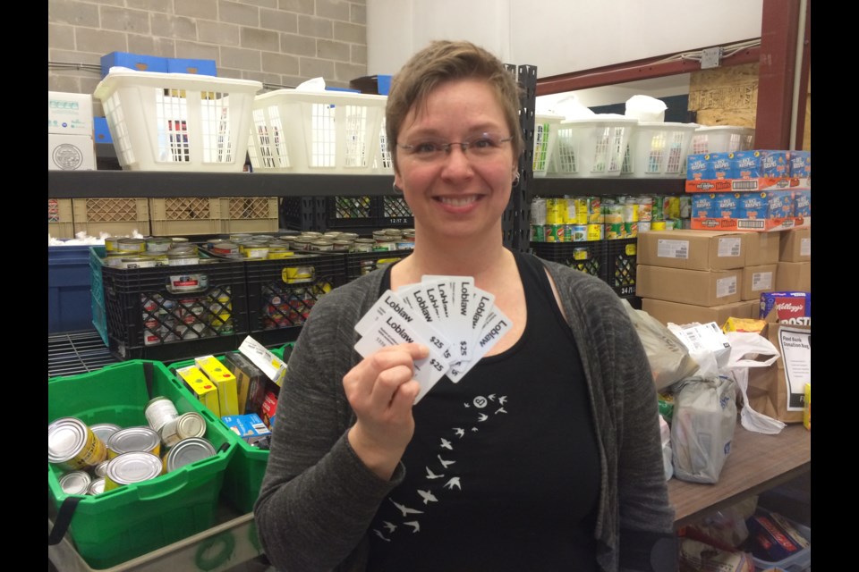 North Bay Food Bank Manager Amber Livingstone holds up donated Loblaw rebate cards.