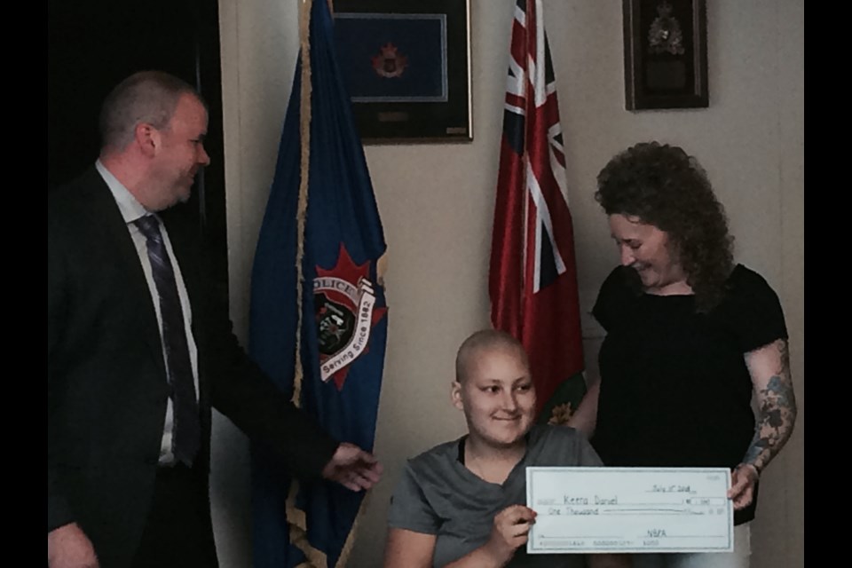 Keera Daniels and her mom Kerri Stiller are presented with a cheque by Detective Constable Darcy Wall on behalf of the North Bay Police Association to help with expenses during Keera's cancer treatments away from home.