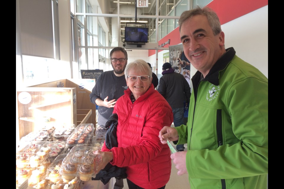 Andrea Raftis buys cupcakes in support of the North Bay and District Humane Society executive director Liam Cullin