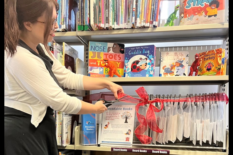 Librarian Robin Benard prepares to cut the ribbon to unveil the new book collection