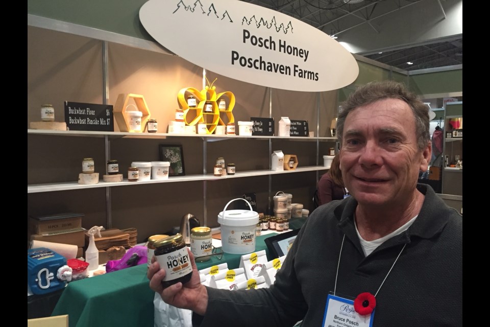 Bruce Posch, owner of Posch Honey, holds up a jar of his black honey. Jeff Turl