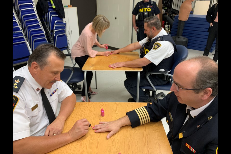 North Bay Police Chief Scott Tod paints the nails of Fire Chief Jason Whiteley.  Photo by Chris Dawson/BayToday. 