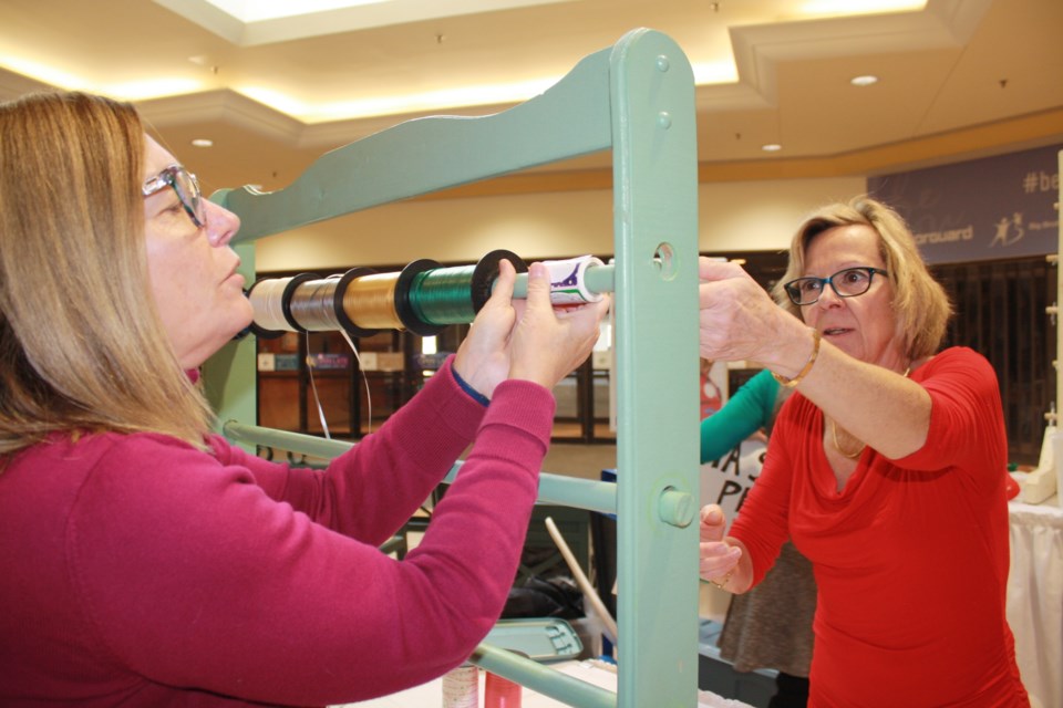Debbie Tremblay (L) and Judy Cousineau (R) assemble the ribbon rack at the gift-wrap booth set-up Sunday at Northgate. Submitted photo.
