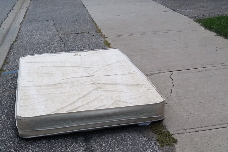 In this file photo, a discarded mattress lies between the road and sidewalk in downtown North Bay.