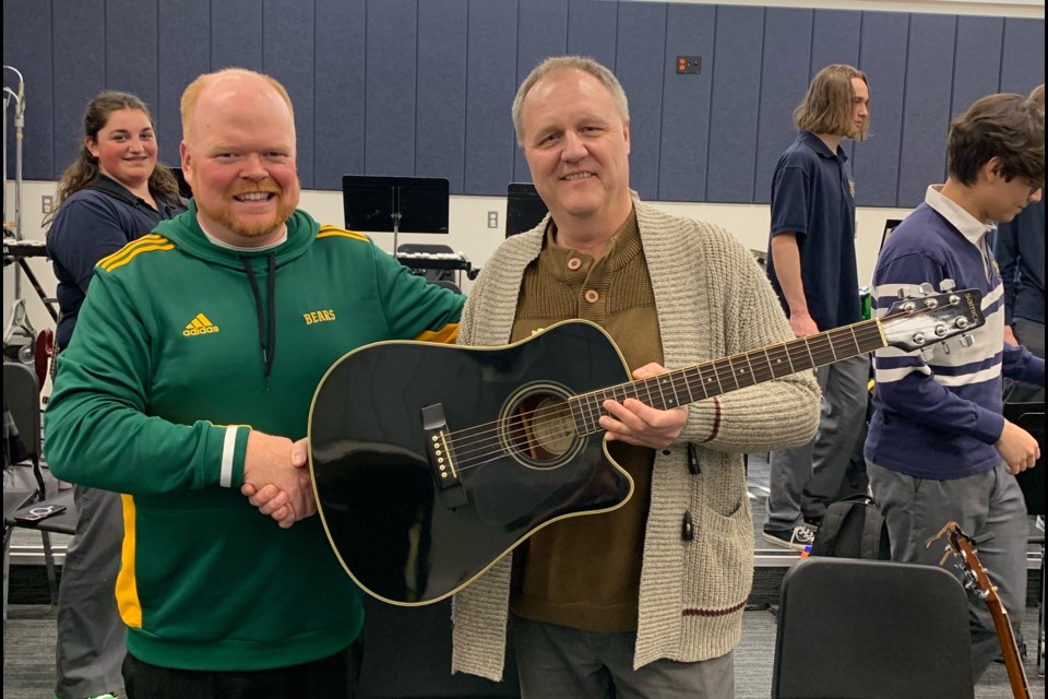Brian Overholt (left) and Gary Davison (right) hold up the donated guitar.  Photo submitted. 