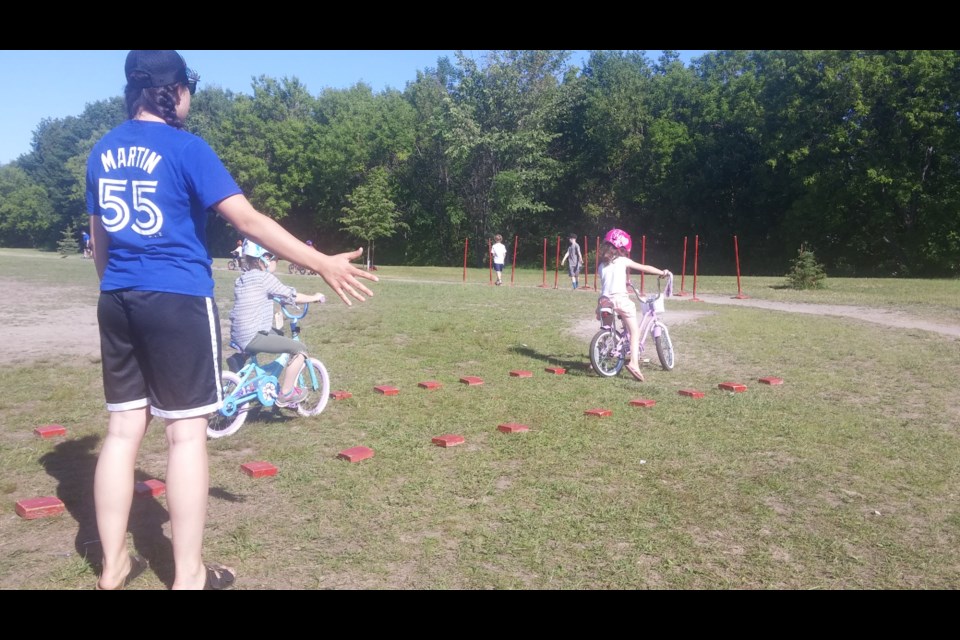 Student volunteer Tiffany Costello helps a Bike Rodeo participant practice looking over her shoulder