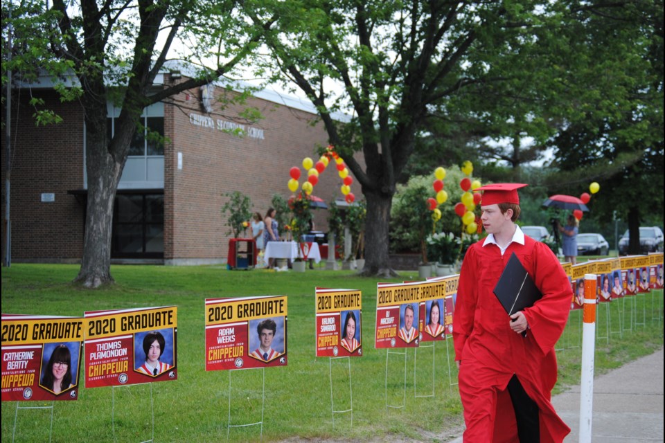 After receiving his diploma, Austin Leblanc walks along an array of signs featuring his fellow Chippewa graduates. Photo: Stu Campaigne