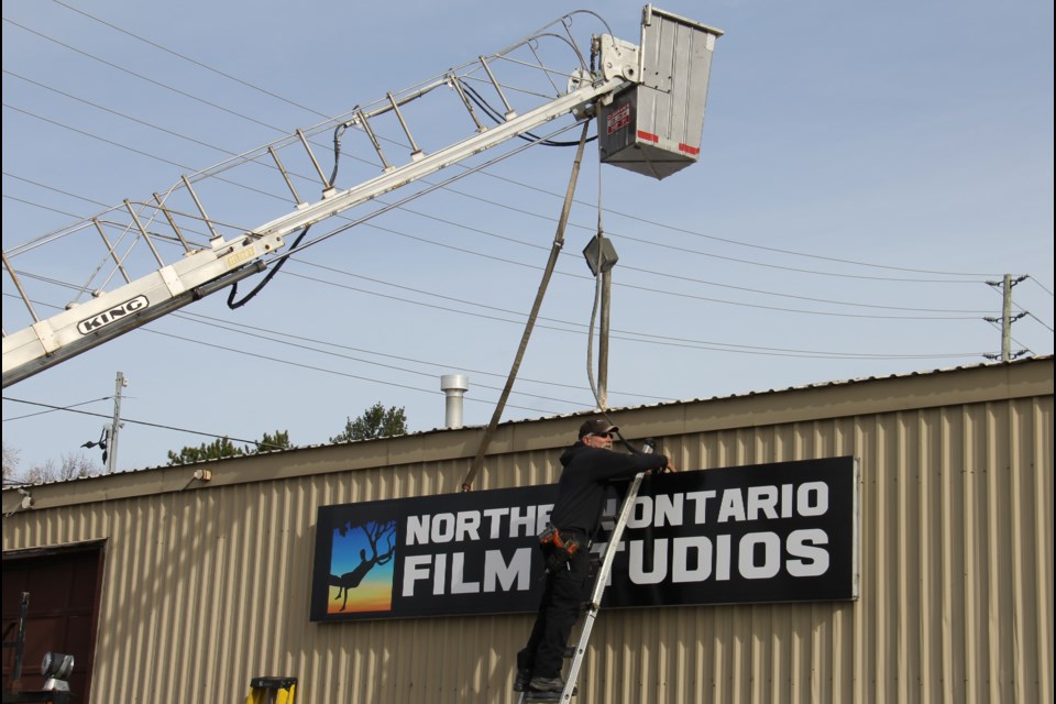 A worker puts the finishing touches to the Northern Ontario Film Studios sign on Gormanville. Photo by Jeff Turl.