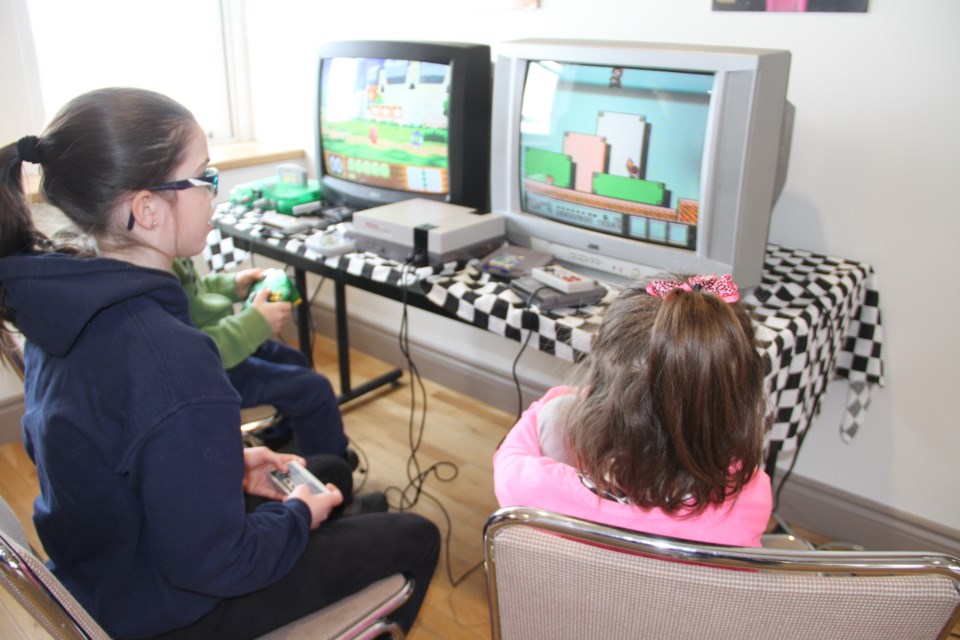 Isabelle Thomas plays Super Mario on an old Nintendo video game console as part of the Retro Video Game event at Discovery Museum.  Photo by Chris Dawson. 