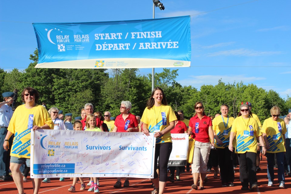 Rhiannon Buffett (right) proudly holds the banner for the survivors' victory lap around the track before the remainder of the participants join them for the 2016 Relay for Life. 