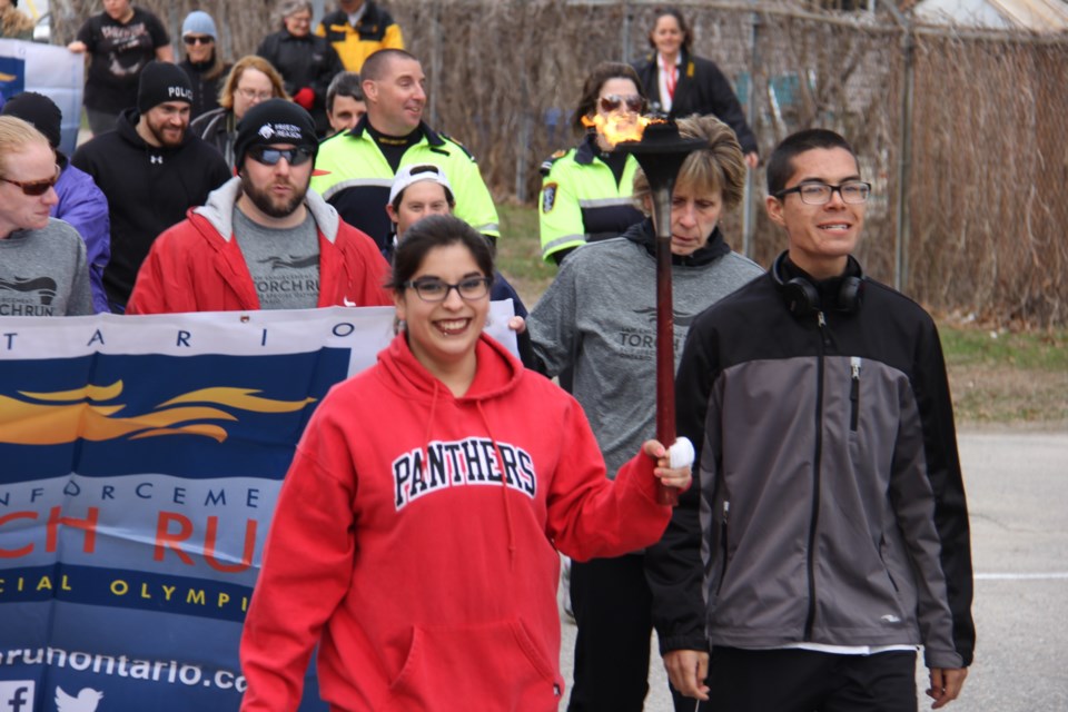 A beaming Zoey Langford leads the Torch Run for Special Olympics at police headquarters this morning. Photo by Jeff Turl. 