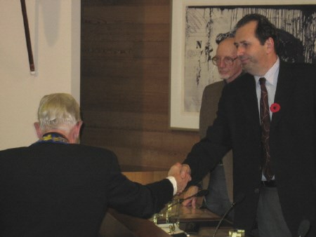 Coun. George Maroosis shakes the hand of outgoing North Bay Mayor Jack Burrows, while Coun. Peter Handley looks on. 