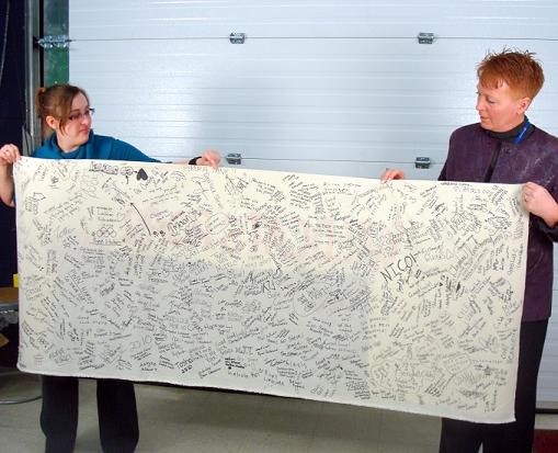 Barnes and Armstrong-Aro show one section of the banner covered in student signatures