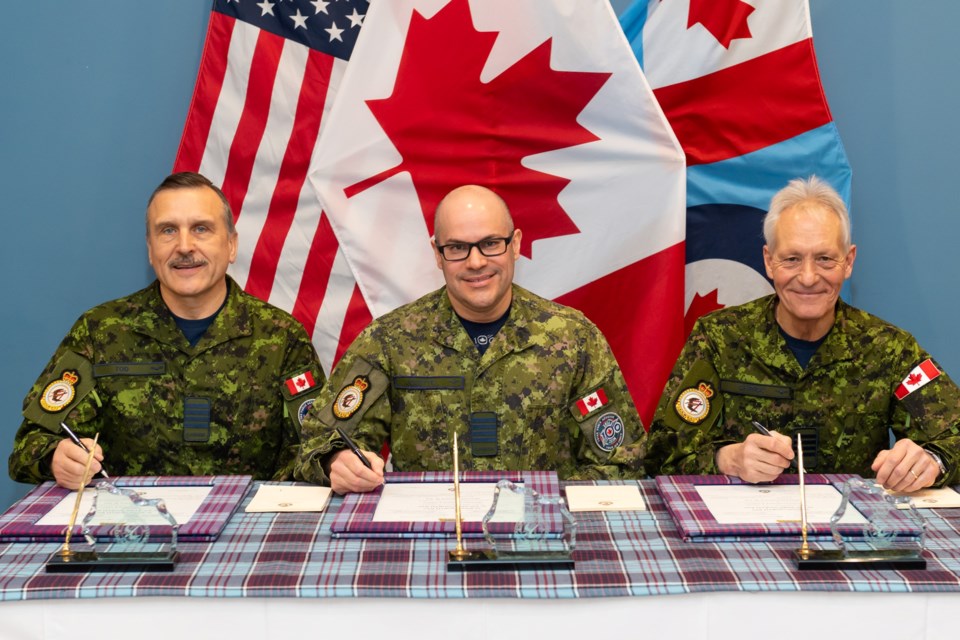 Incoming 22 Wing Honorary Colonel Scott Tod, 22 Wing Commander Colonel Richard Jolette and outgoing 22 Wing Honorary Colonel Peter Chirico signing the change of command scrolls.