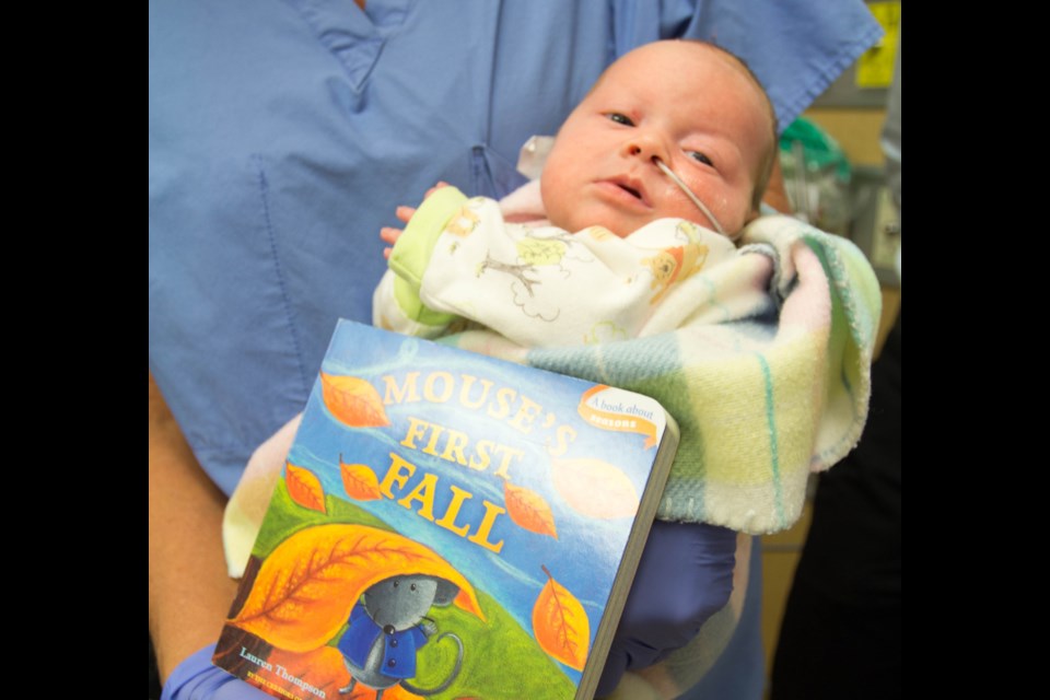 Baby Emille O’Reilly with one of the new books from the lending library. Submitted.