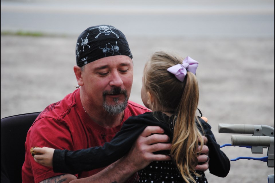 Brad Martin, victim of a Lakeshore Drive collision ten months ago, is welcomed at a party in his honour by his granddaughter, Sunday. Photo by Stu Campaigne.