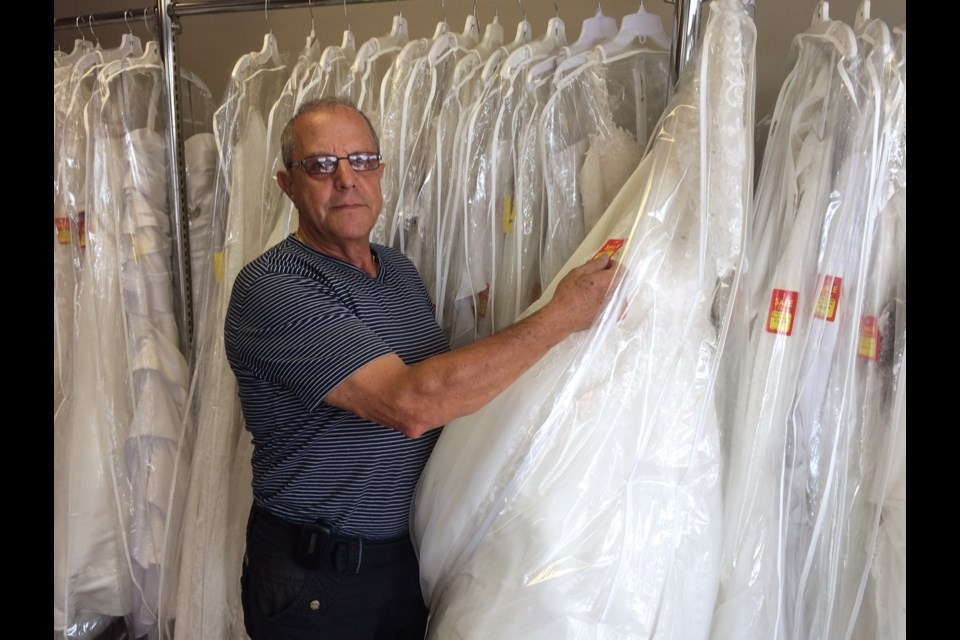 Tony Cerasia checks out one of the wedding dresses that is part of a final closing sale. Cerasia Fashions is closing after 45 years. Photo by Jeff Turl.