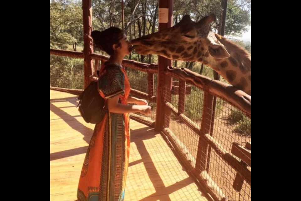 Naila Aqbal shares a kiss with a giraffe in Kenya. Photo provided by Naila Aqbal. 