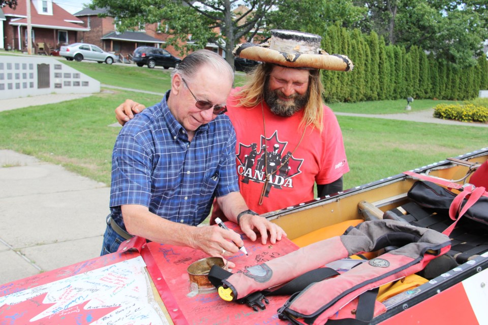 Legion Br. 23 Vice President Jim Thompson signs the canoe of Mike Ranta. The adventurer is crossing Canada to raise the issue of PTSD among veterans. Photo by Jeff Turl.