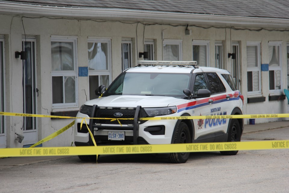 A North Bay police officer guards a taped-off area around a room at the Dolphin Motel on Lakeshore Drive.