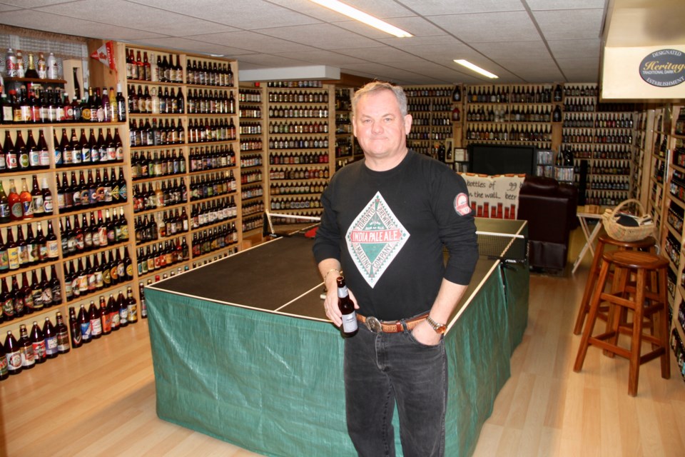 Tony Matheson stands in front of his massive full beer bottle collection.  Photo by Chris Dawson. 