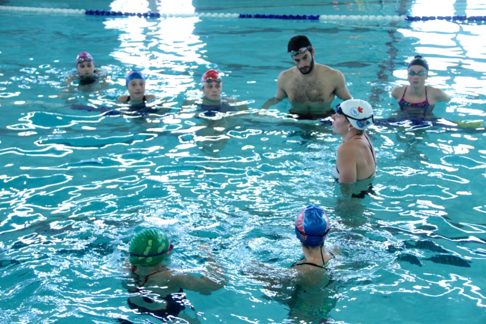 Two-time Canadian Olympian Martha McCabe explains some stroke techniques to Titans swimmers at the YMCA . Photo by Chris Dawson. 