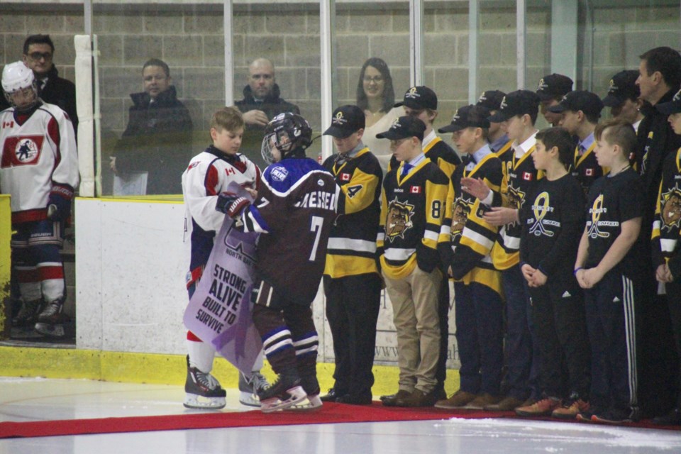 Nolan Newton hands over a purple Trappers banner to cancer survivor Brock Chessell of the Huron-Perth Lakers.   Photo by Chris Dawson.  