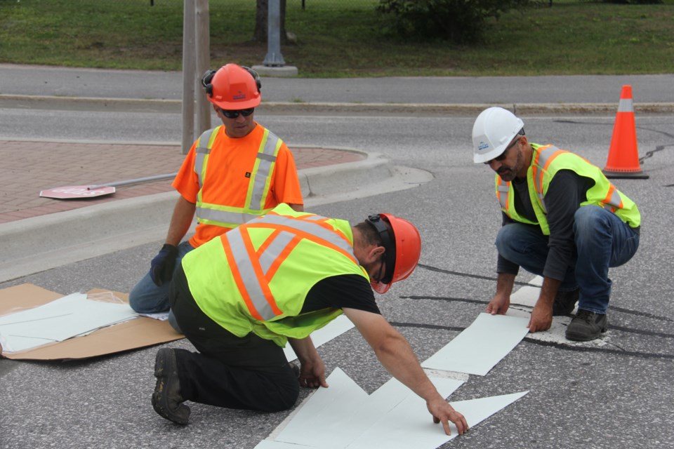 Marc Boisvert, Gilles Belanger and Franco Ricci lay out the precut directional arrow on the Gormanville roundabout. Jeff Turl/BayToday.