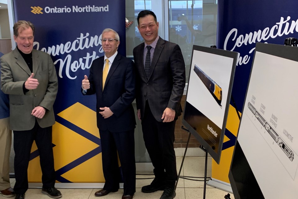 Stan Cho, Associate Minister of Transportation (right) and MPP Vic Fedeli (middle) stand near renderings of the new Northlander Train.  Photo courtessy Chris Dawson/BayToday. 