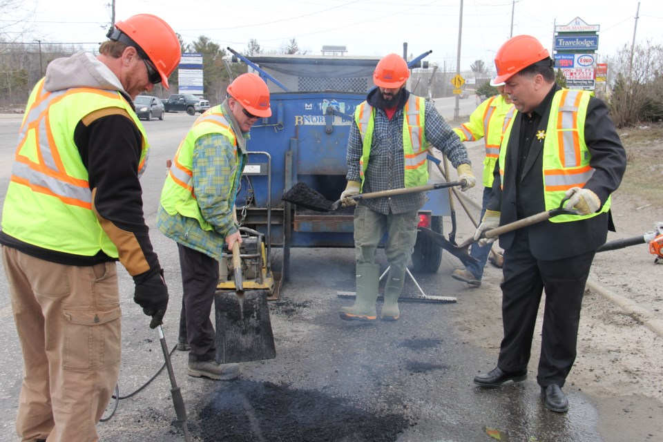 Recycled hot mix asphalt will save the city time and money. In the background is the hotbox, used to transport the mix. Here city workers Steve McLaren, David Pledge, Brandon Neault and Councillor Jeff Serran fill a pothole on Seymour Street. Photo by Jeff Turl. 