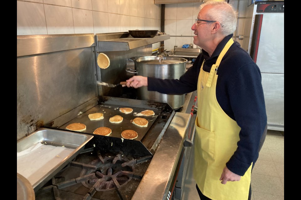 Nipissing MPP Vic Fedeli flipping pancakes at the Paramedics and Pancakes wellness check 