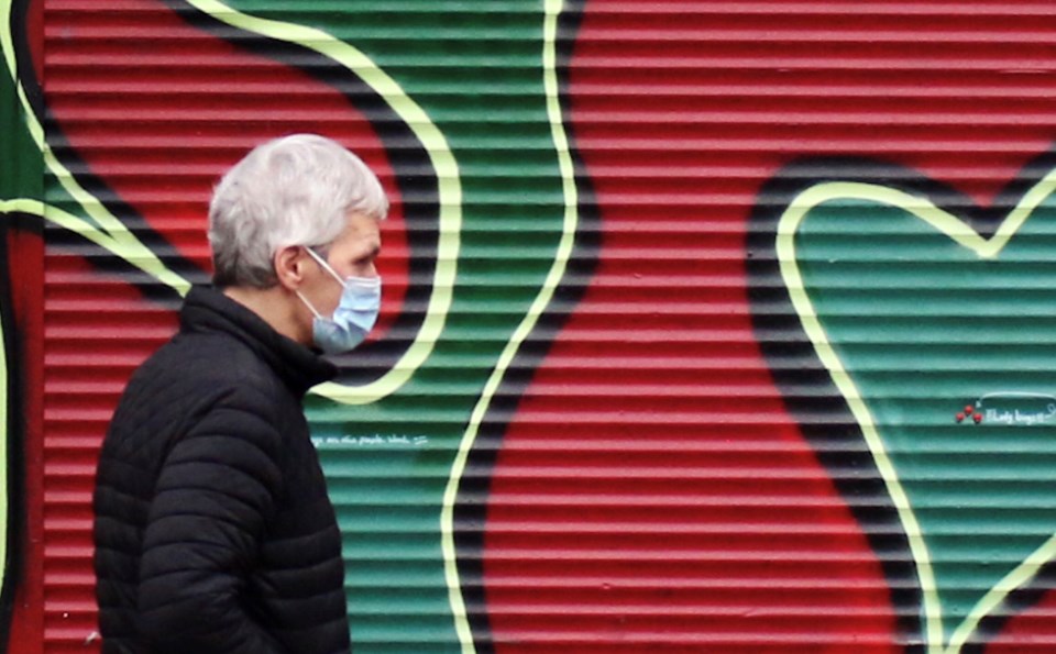 Man in mask past grafitti - rk