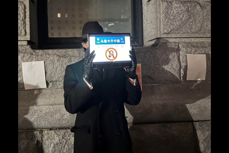 Andrew, who declined to have his last name published, silently protested by displaying on his tablet a replica of the sign from a Shanghai street where protesters gathered to mourn the dead in a Xinjiang apartment fire and demand an end of the Chinese Communist Party's strict pandemic lockdowns. Behind him are blank sheets of paper, like the ones waved last weekend by dissidents in China.
