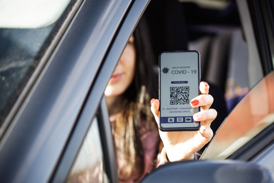 Woman in car with covid passport - GettyImages-Lerexis