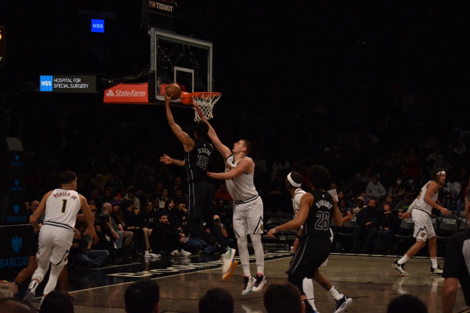 #15 Center Denver Nuggets Nikola Jokic contests #33 Brooklyn Nets Center Nic Claxton's shot at the rim.