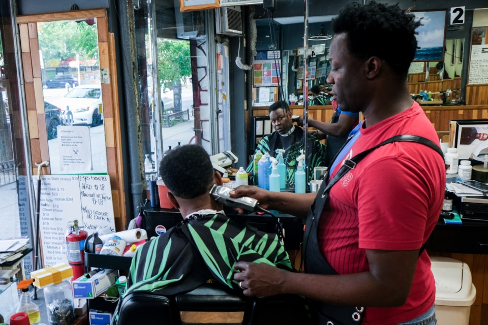 Patrick Goby, who has been in the business for more than two decades, buzzes a client’s hair at his salon on Nostrand Ave. 
