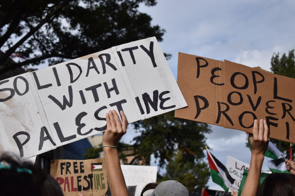 Protestors holding signs while listening to a speech at the protest.