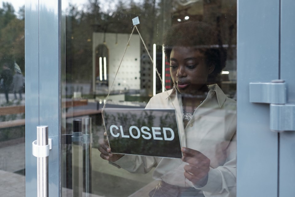 young-african-shop-assistant-hanging-closed-sign-o-2021-12-09-05-53-21-utc