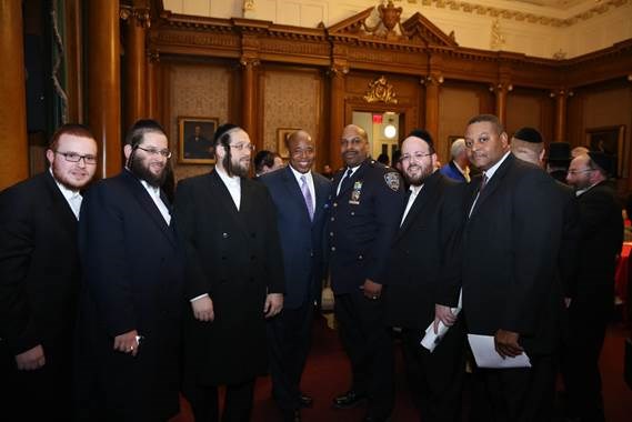 Brooklyn Borough President Eric Adams joins (from left to right) community activist Yanky Eisdorfer, Administration for Children's Services representative Pinny Ringel, executive director of JCC of Greater Williamsburg Rabbi Moshe Indig, 88th Precinct commanding officer Deputy Inspector Scott Henderson, special assistant to Borough President Adams Joel Eisdorfer and Patrol Borough Brooklyn North Lieutenant Marvin Luis at a pre-Passover community open dialogue in the courtroom of Borough Hall. Photo: Yossi Goldberger