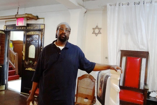 Rabbi Baruch Yehudah stands where his congregation worships in the basement level of his synagogue 