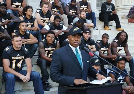 Brooklyn Borough President Eric L. Adams, sporting his new Brooklyn Bolts cap, welcomes the Bolts of the Fall Experimental Football League (FXFL), the borough¹s first professional football team since 1949, at a rally on the steps of Brooklyn Borough Hall; in the background are members of the Bolts. Photo: Kathryn Kirk/BP¹s Office