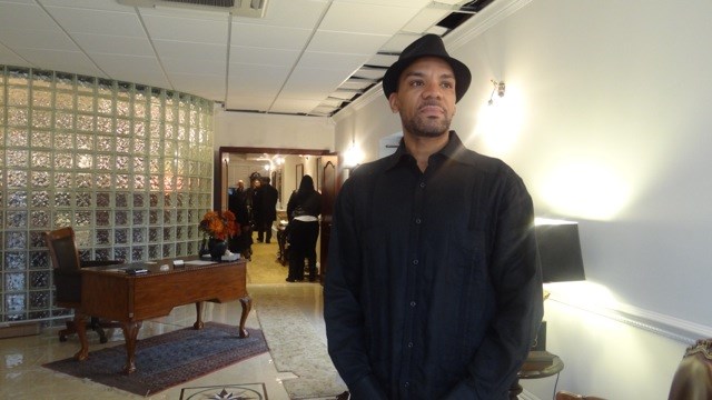 Samad Razzaq, son of Abdullah Abdur-Razzaq, stands right inside of the funeral parlor holding the memorial for his father's passing