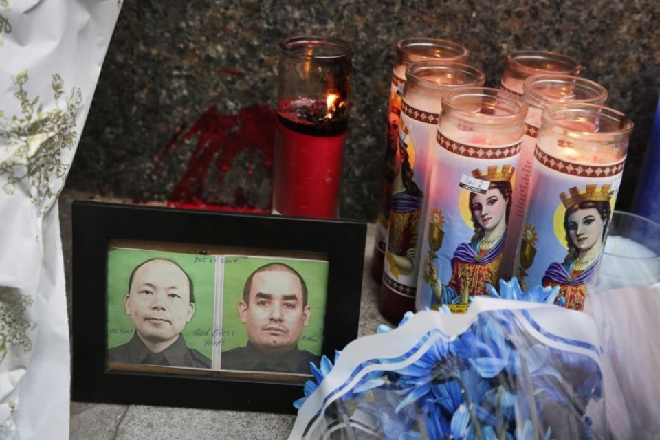 Photos of the NYPD Officers Weinjen Liu (left) and Rafael Ramos are displayed at the Bed-Stuy memorial near where they were killed Saturday. Photos: Mark Lennihan/AP