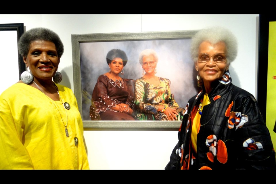Phyllis Bynum and June Terry stand stand by the photo where they were featured for the book, &#8220;Afros: A Celebration of Natural Hair&#8221;