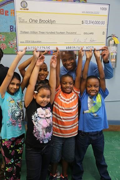 Brooklyn Borough President Eric L. Adams joins students from PS 193 Gil Hodges in raising up an oversized check in the amount of $13,314,000 made out to