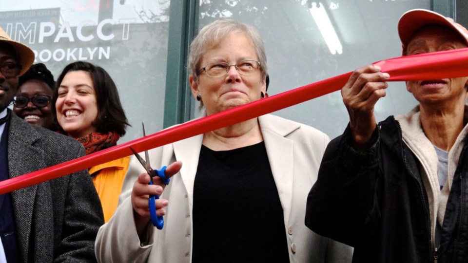 Deb Howard, executive director for the newly named IMPACCT Brooklyn, prepares to cut the ribbon at one of its new storefront offices, located at 1124 Fulton Street