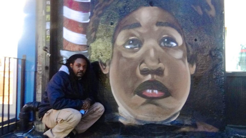 Artist Vince Ballentine stands in front of a mural he just completed of the Notorious B.I.G., located on the corner of Fulton Street and St. James Place