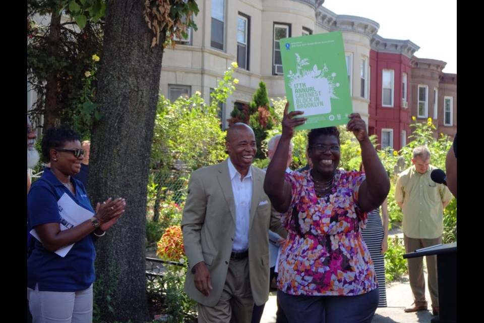 300 25th Street Block Association President holds up the award for the 'Greenest Residential Block in Brooklyn'.
