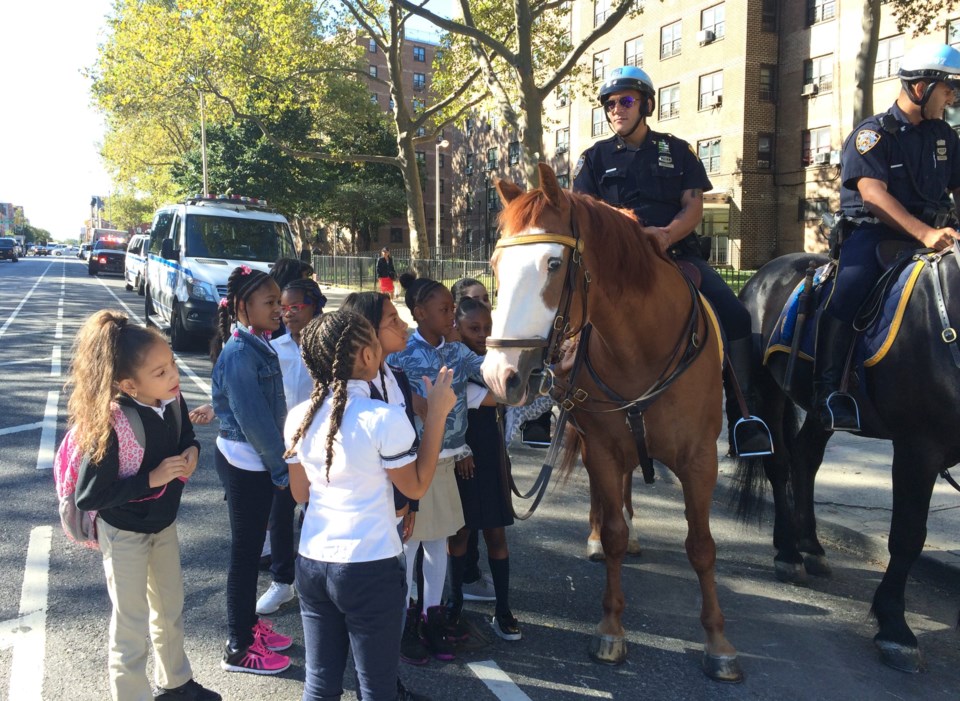 Students at Thursday's event pet a mounted police horse. A group of girls from P.S. 59 approach mounted police horse at backpack giveaway event.